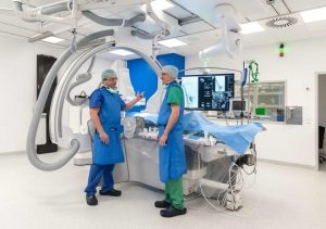 Prof. Dr. Jens Theysohn (li.) und PD Dr. Christoph Mönninghoff, beide Oberärzte in der Radiologie, vor der neuen Angiographie-Anlage „Artis Q“. Die Patientin ist steril abgedeckt. Quelle: UK Essen