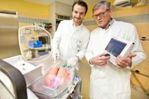 Dr. Norman Zinne (l.) und Professor Dr. Axel Haverich an einem Organ Care System (OCS), das eine Schweinelunge enthält. Professor Haverich hält die Steuereinheit für das OCS. Foto: Karin Kaiser/MHH