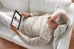 Mann auf Sofa mit Tablet in der Hand