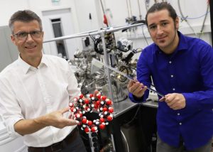 Prof. Dr. Dario Anselmetti von der Universität Bielefeld mit einem Kugelmodell eines Cyclodextrin-Moleküls – Basis der neuen Nanomembranen. Der Doktorand Niklas Biere hält das Modell des Kraftsensors, mit dem die Membran abgetastet wurde. Foto: Universität Bielefeld/C. Pelargus