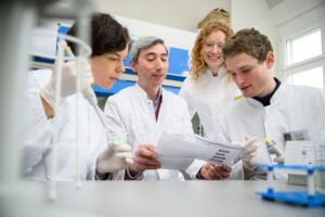 Die Medizinstudierenden Luise Schäfer (l.) und Luca Huth (r.) untersuchen im Universitätsklinikum Würzburg mit Martina Prelog und Giovanni Almanzar die zelluläre Immunabwehr und Antikörperantworten von Hochrisikopatientinnen und -patienten. Foto: UKW / Daniel Peter