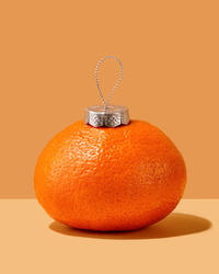 Christmas concept. Tangerine holiday ornament on beige background.