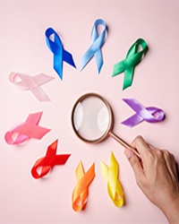 Hands,Holding,Magnifier,With,Colorful,Ribbons,On,Pink,Background,,Cancer