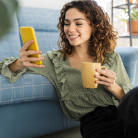 Curly,Haired,Woman,Sitting,On,Sofa,With,A,Cup,Of
