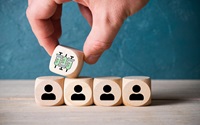 hand placing a cube with a syringe symbol on top of a line of cubes with person symbols symbolizing allocation problem of vaccination
