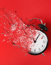 Time is running out. Black alarm clock vanishing on red background, top view
