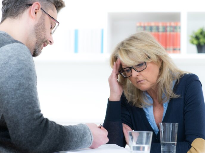 Patientin mit Kopfschmerzen, Mann macht Notizen