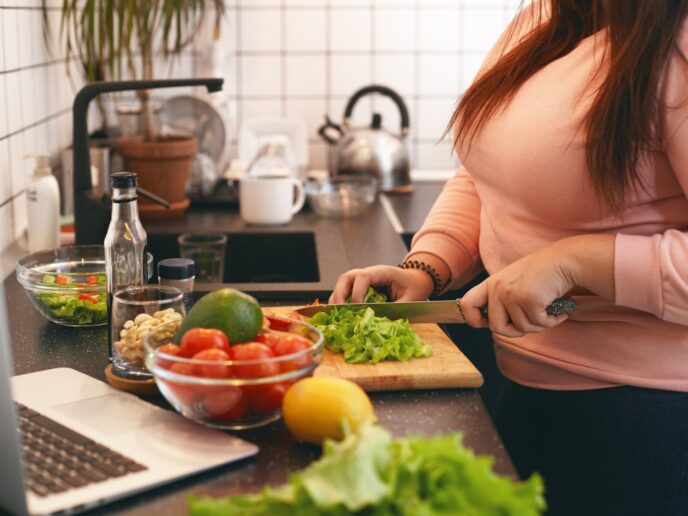 Frau mit Übergewicht bereitet sich in ihrer Küche gesundes essen zu