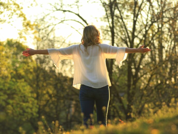 Frau in der Natur breitet die Arme aus