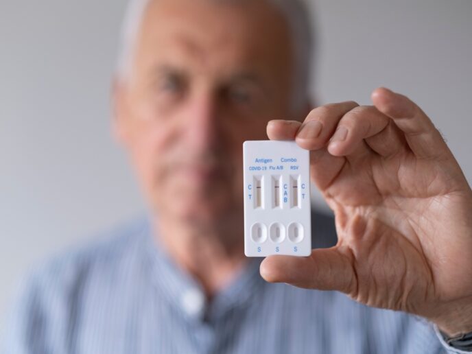 Senior mit Test für Influenza, RSV und COVID-19