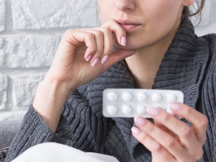 Frau betrachtet nachdenklich Tabletten