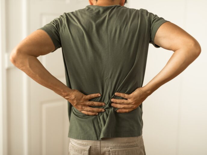 Mann hält sich den unteren Rücken.