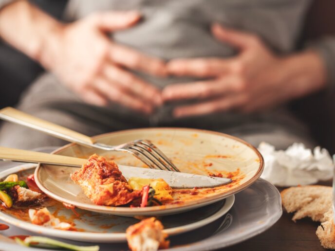 Mann vor leerem Teller hält sich den Bauch