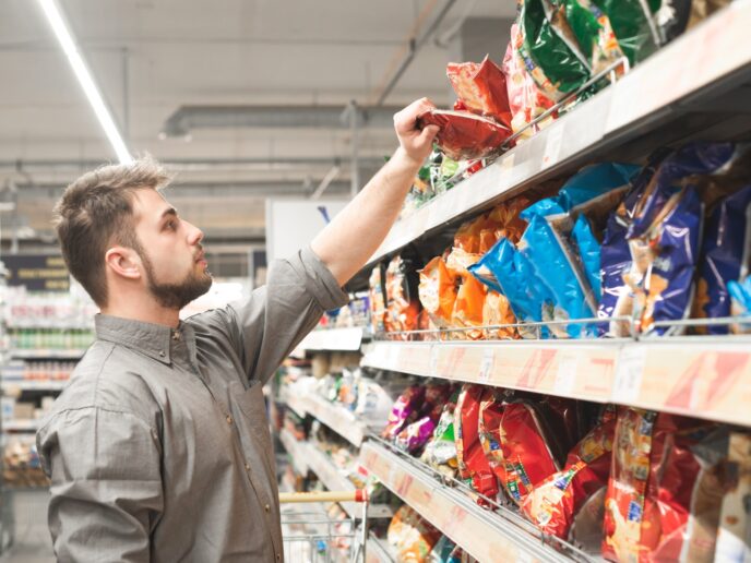 Mann vor dem Snack-Regal im Supermarkt