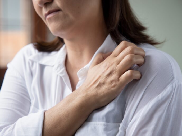 Frau kratzt sich an der Schulter