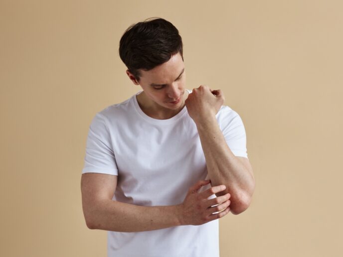 Mann kratzt sich am Ellenbogen