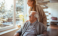 Young woman caring for elderly man in a sunlit room with winter scenery outside
