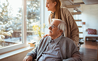 Young woman caring for elderly man in a sunlit room with winter scenery outside