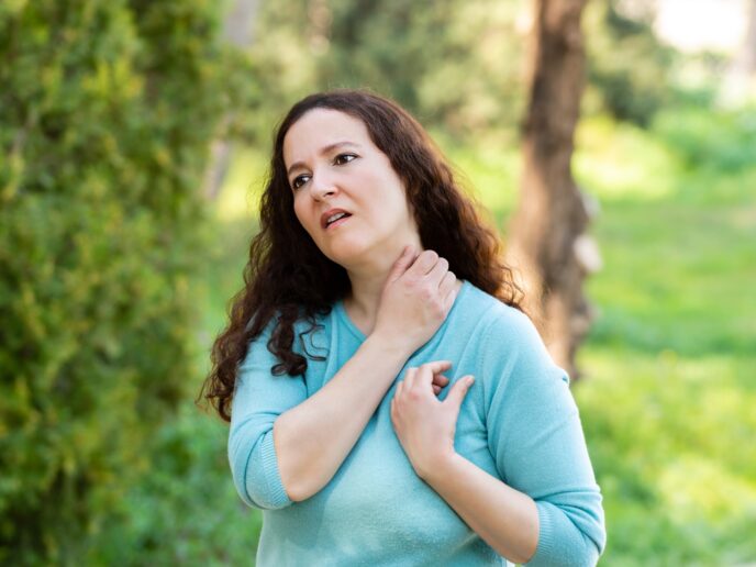 Frau in der Natur kratzt sich am Hals