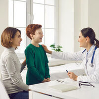 Friendly,Female,Doctor,Talking,To,Child,And,His,Mother,During