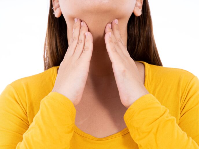 Frau tastet ihren Hals ab