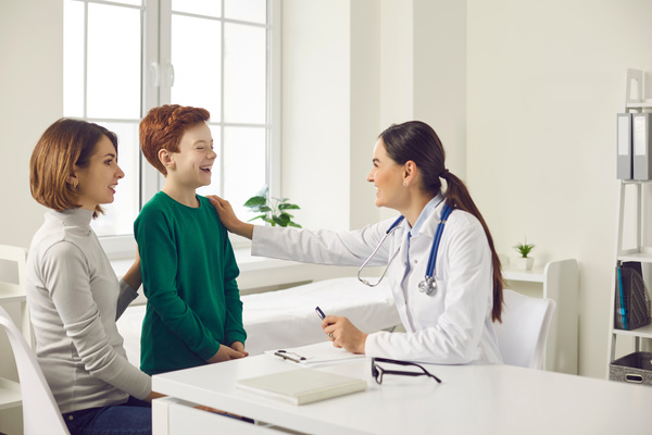 Friendly,Female,Doctor,Talking,To,Child,And,His,Mother,During