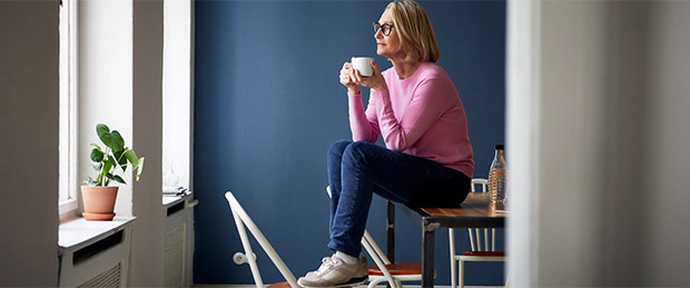 Foto: Eine Frau sitzt mit einer Tasse in der Hand